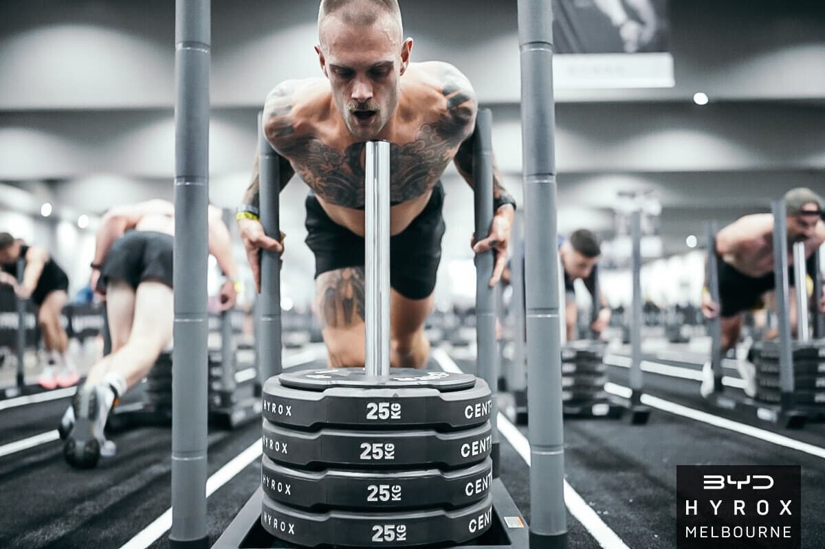 Performance coach Jordon Mudge driving a sled push during a HYROX race in Melbourne